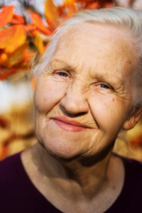 Elderly woman smirking in the outdoors during the Fall.